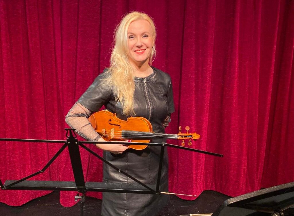 Beata Angelbjörk med violin framför rött draperi.